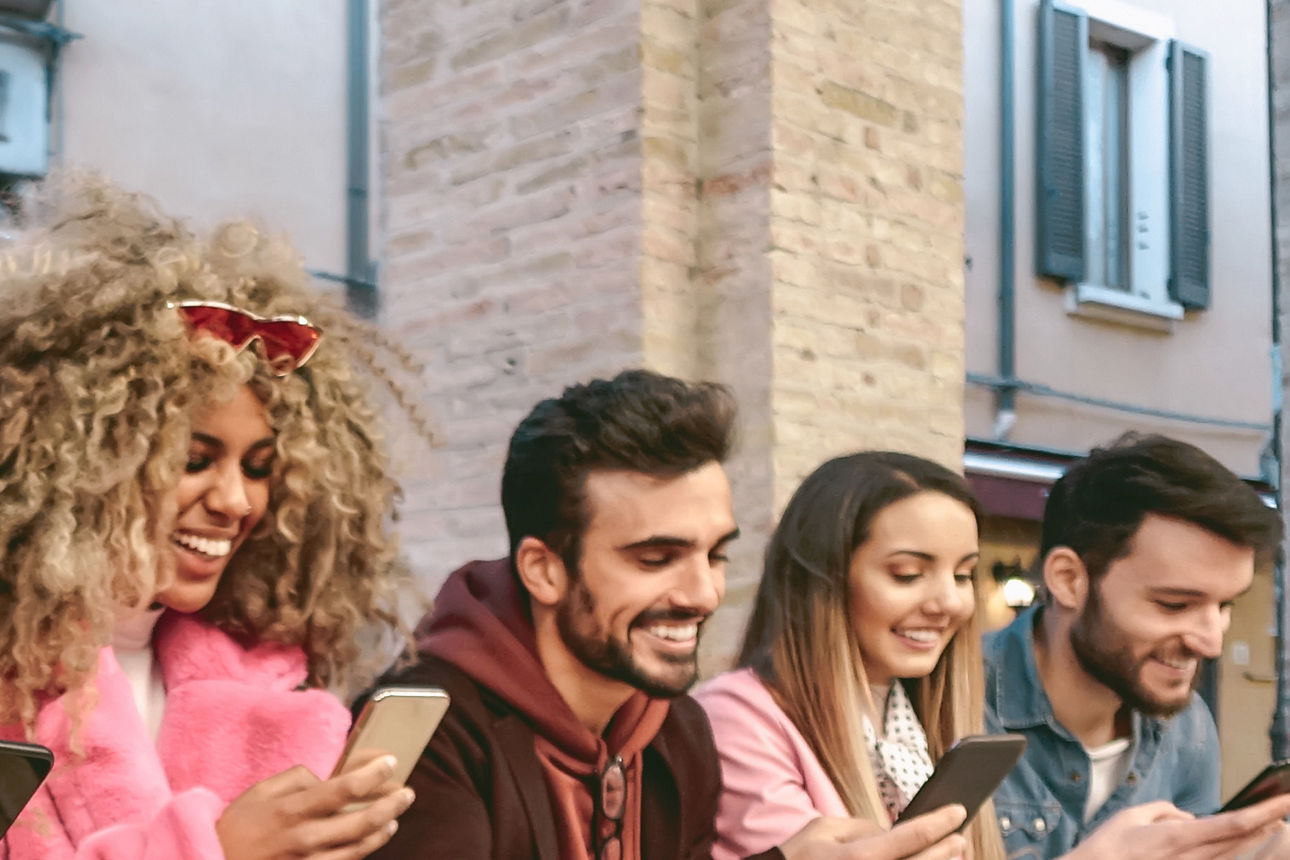 Lachende Gruppe von jungen Menschen mit Smartphone
