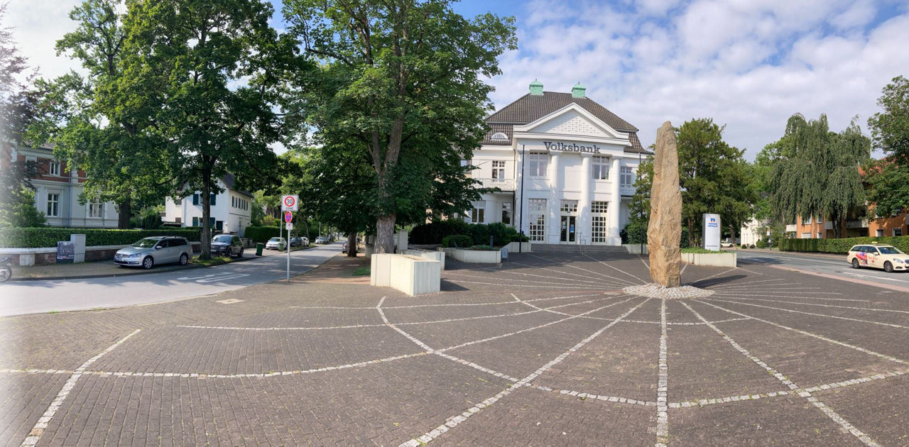 Weißes Gebaude mit Säulen und einem Platz im Vordergrund