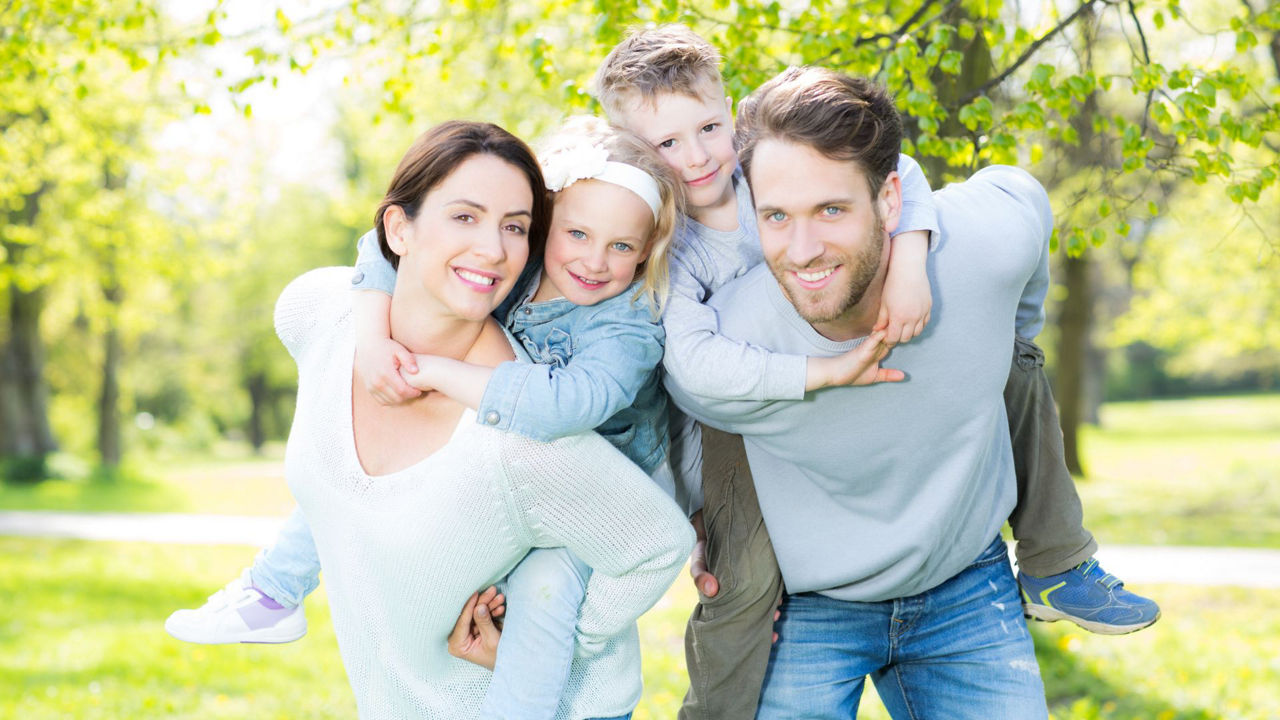 Eine junge Familie trägt ihre Kinder Huckepack