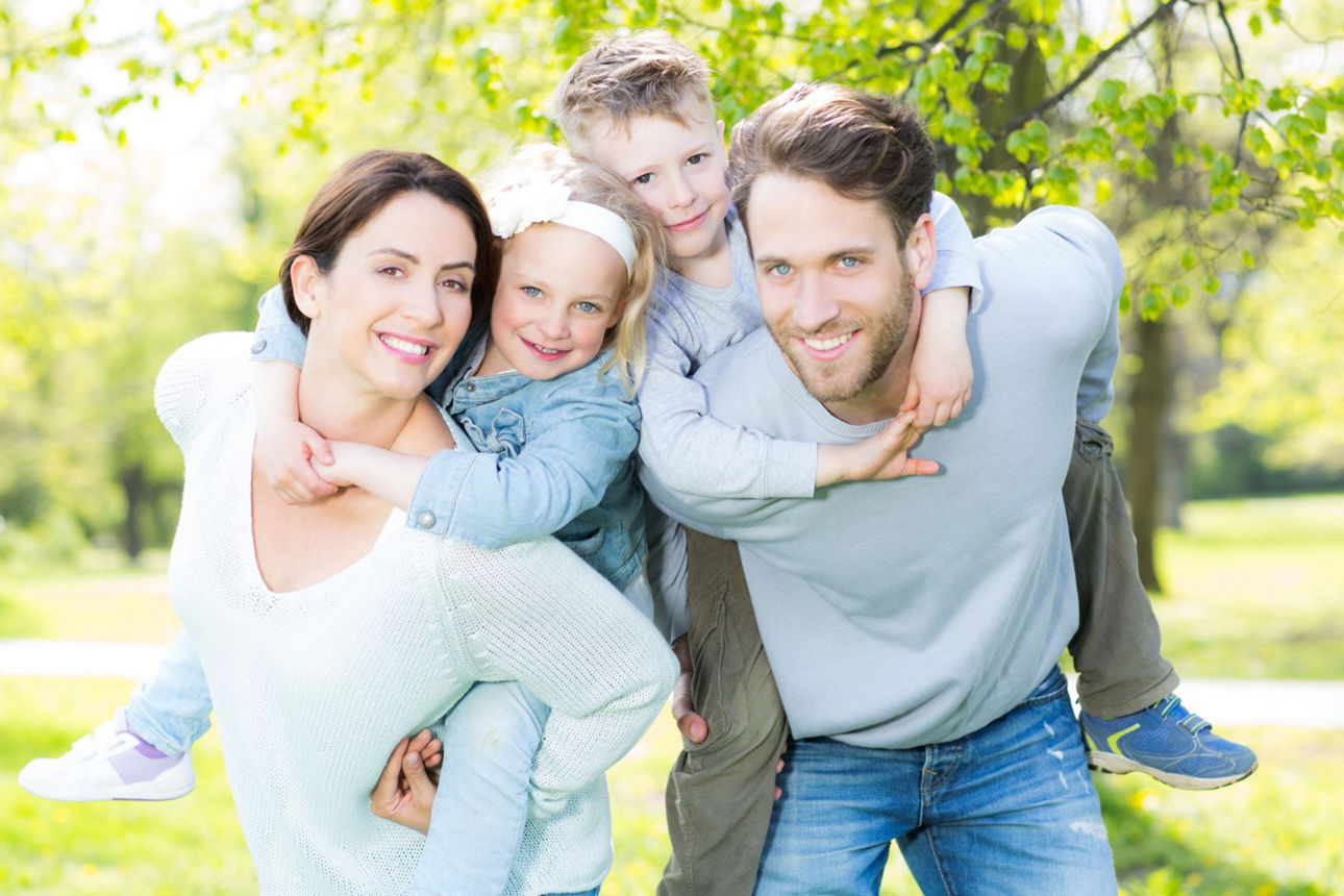 Eine junge Familie trägt ihre Kinder Huckepack