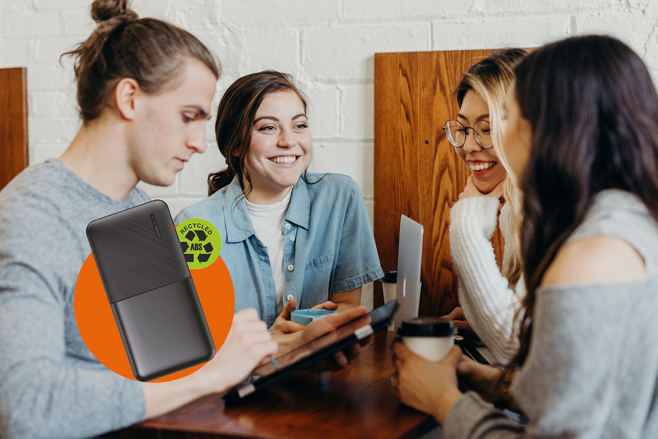 Vier Jugendliche sitzen beisammen mit Laptop und Tablet. Auf dem Bild ist ein Störer mit einer Powerbank..
