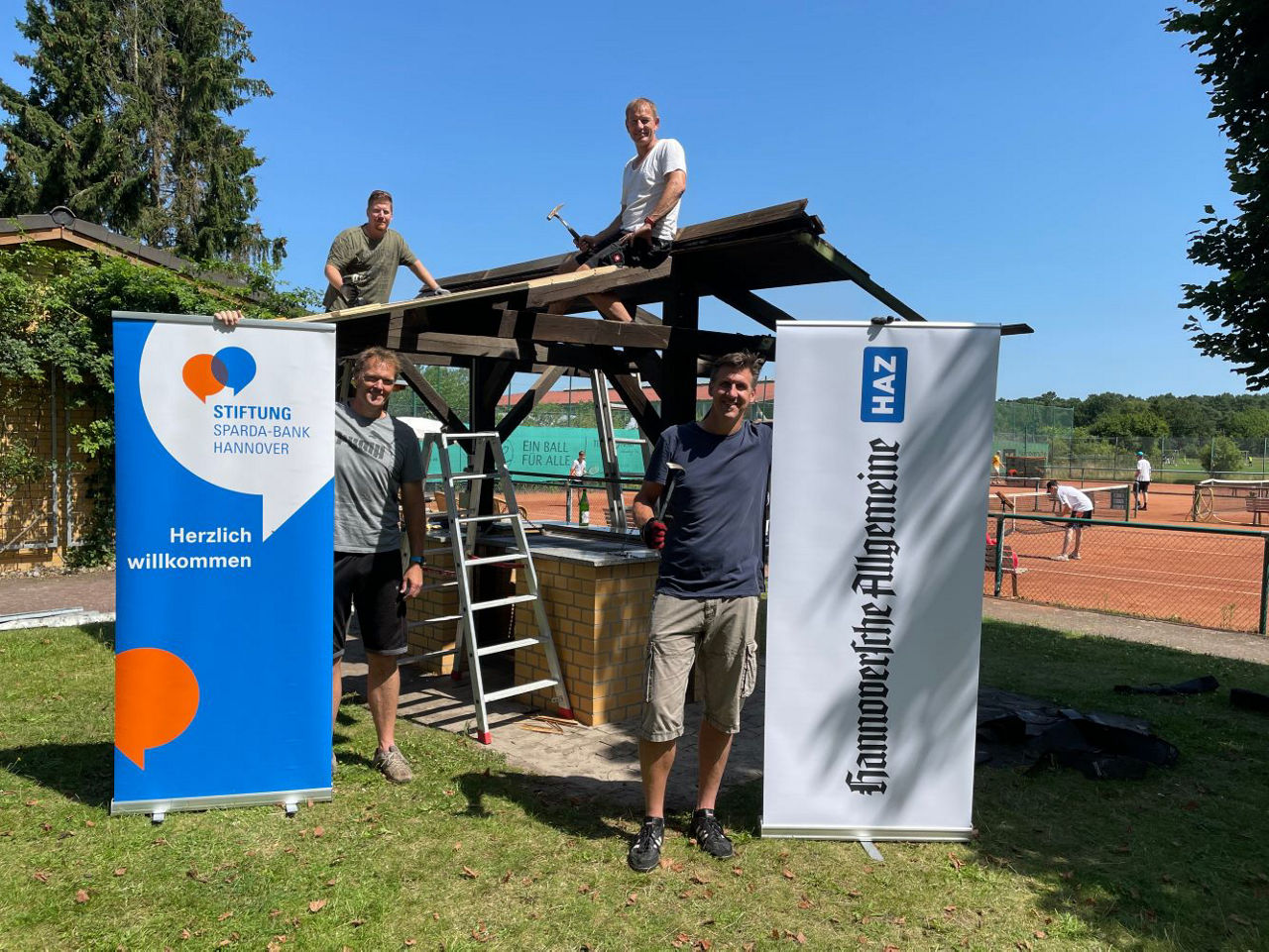 Mehrere Männer arbeiten an einer kleinen Hütte.