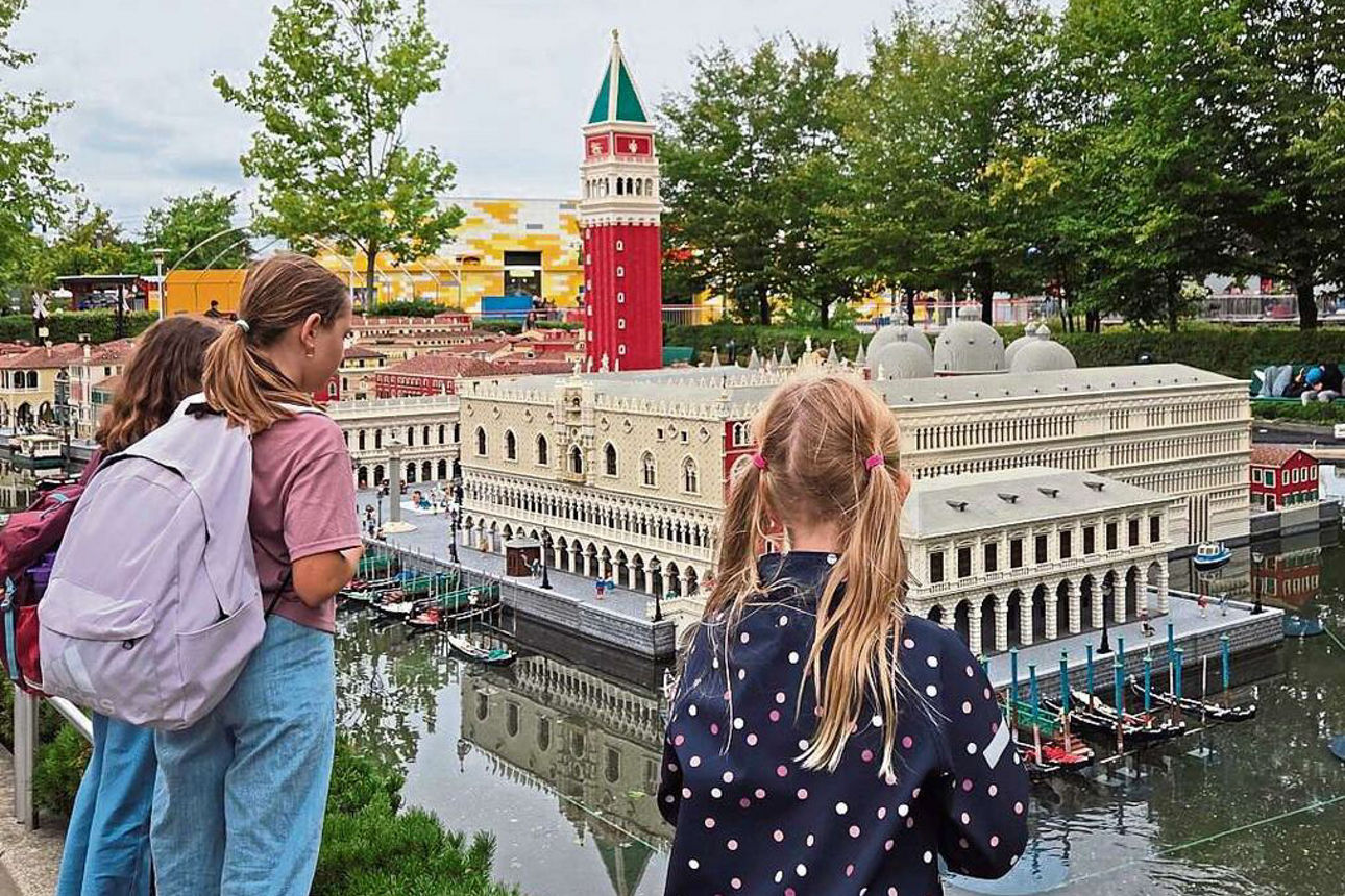 Drei Kinder stehen im Legoland vor einer Miniaturstadt.