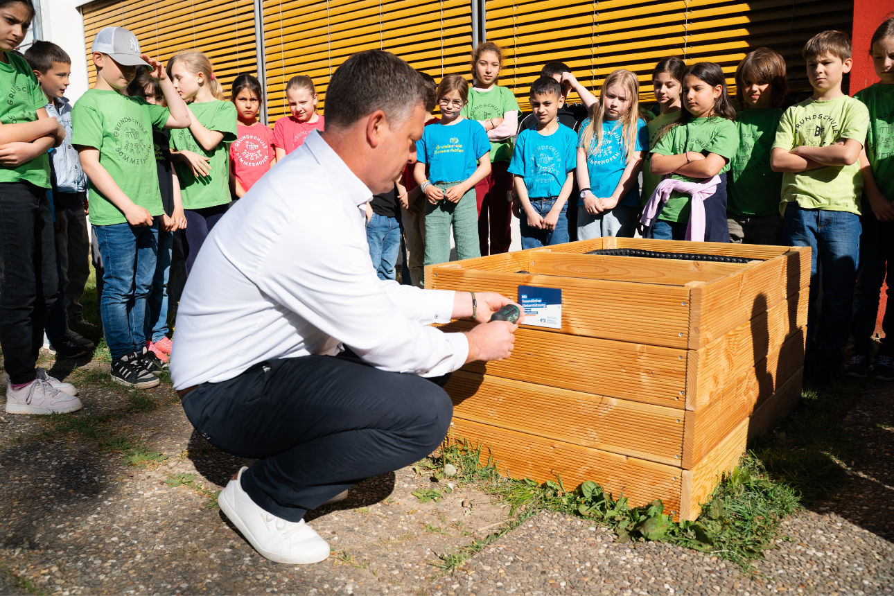 Volksbank-Schild wird am Hochbeet angebracht