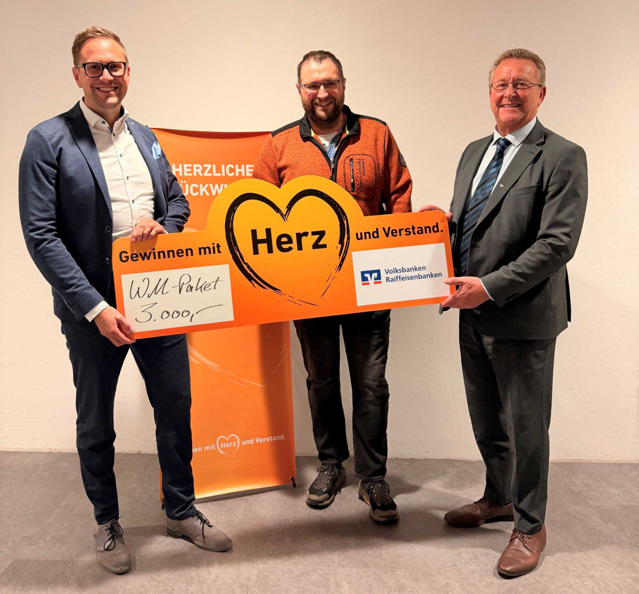Hier ist die Bildbeschreibung für das neu hinzugefügte Foto:  Bild 24 (Scheckübergabe Gewinnsparen): Drei Männer halten gemei