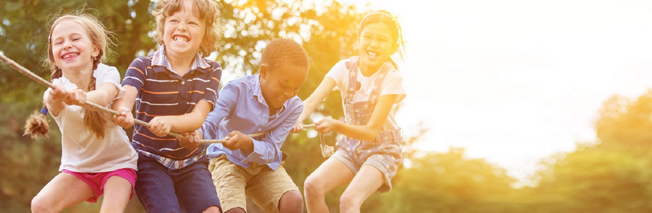 Eine Reihe an Kindern ziehen gemeinsam an einem langen Seil