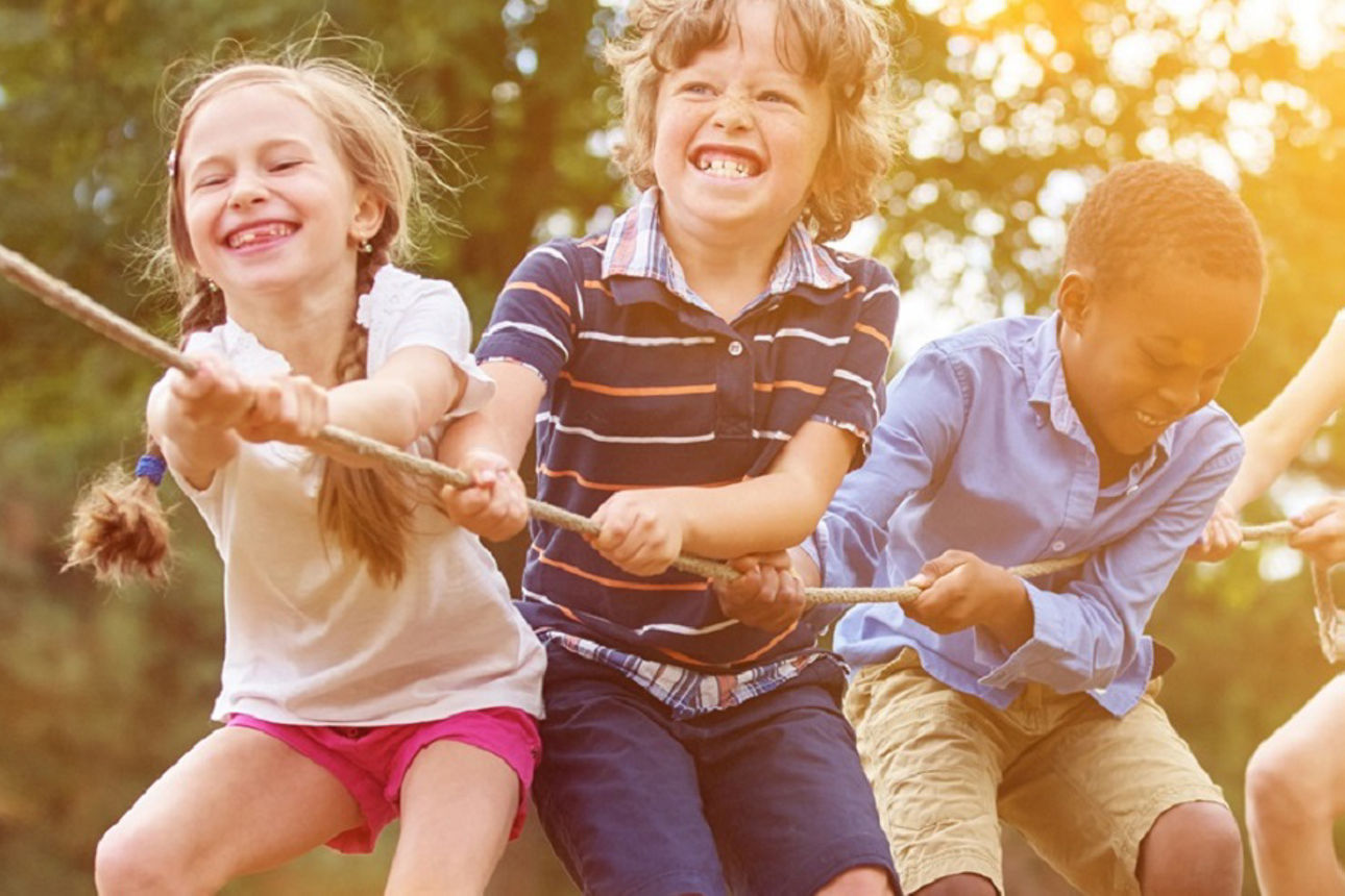 Eine Reihe an Kindern ziehen gemeinsam an einem langen Seil