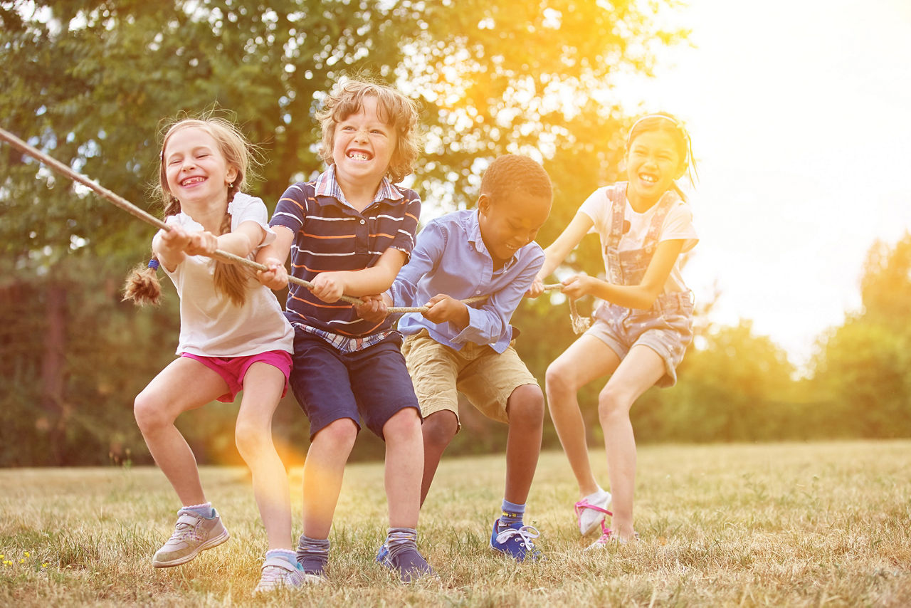 Eine Reihe an Kindern ziehen gemeinsam an einem langen Seil