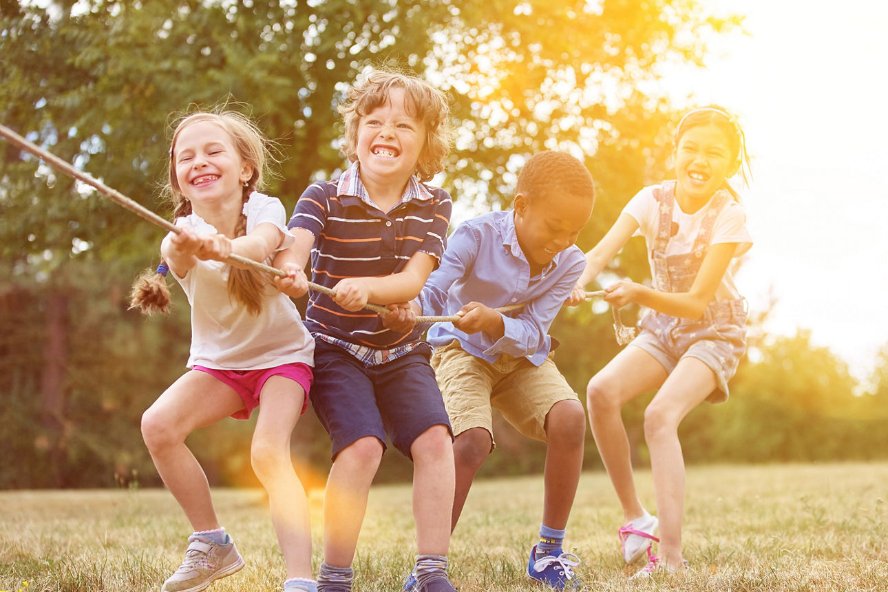 Eine Reihe an Kindern ziehen gemeinsam an einem langen Seil
