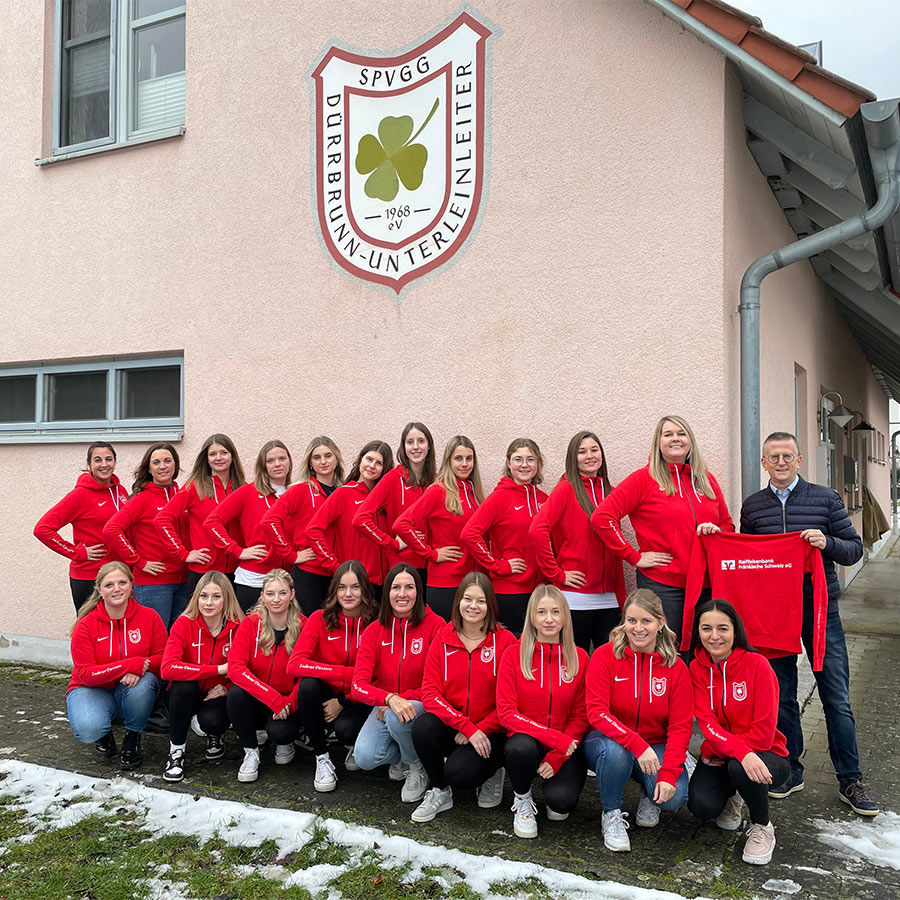 Weibliche Sportler in Uniform, die vor einem Gebäude posieren.