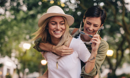Freundinnen die sich Huckepack tragen und lachen