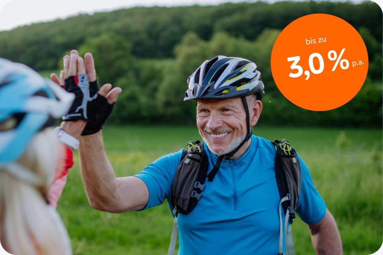 Ein älteres Paar ist mit dem Fahrrad unterwegs und klatscht sich freudig ab