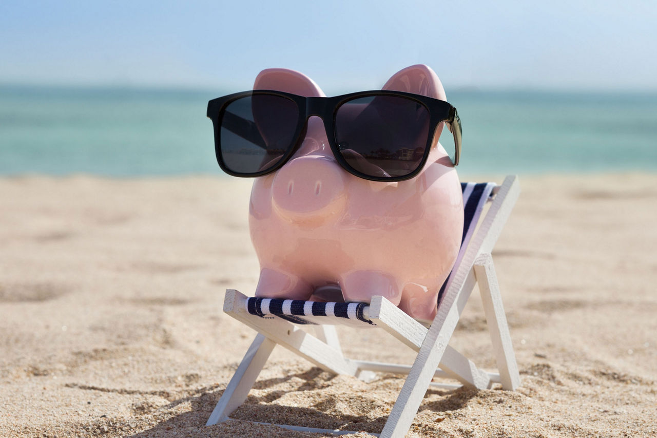 Sparschwein am Stand auf Sonennstuhl mit Sonnenbrille
