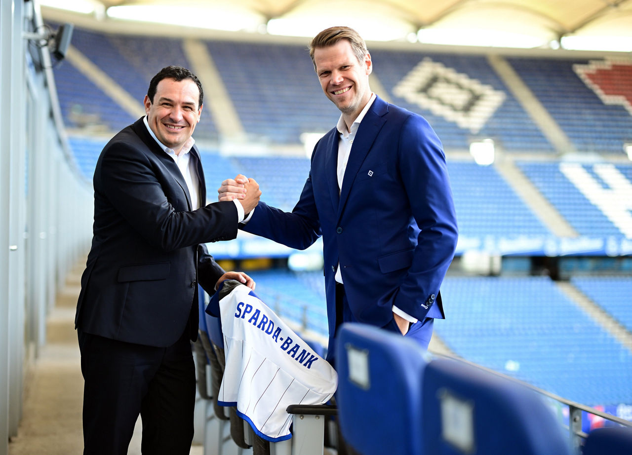 Zwei Personen machen ein Handshake auf der Tribüne des Volksparkstadions
