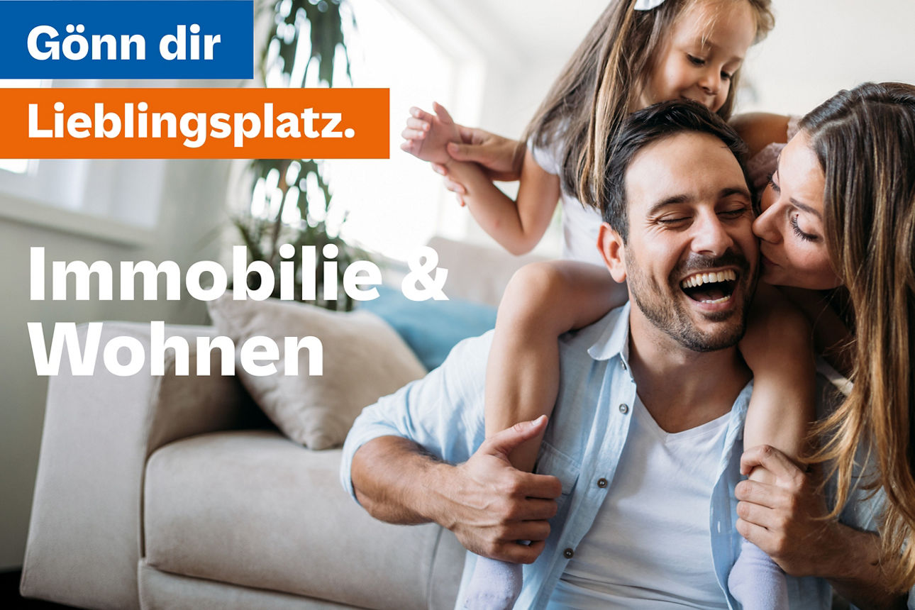 Frau küsst Mann mit Kind auf der Schulter im Wohnzimmer