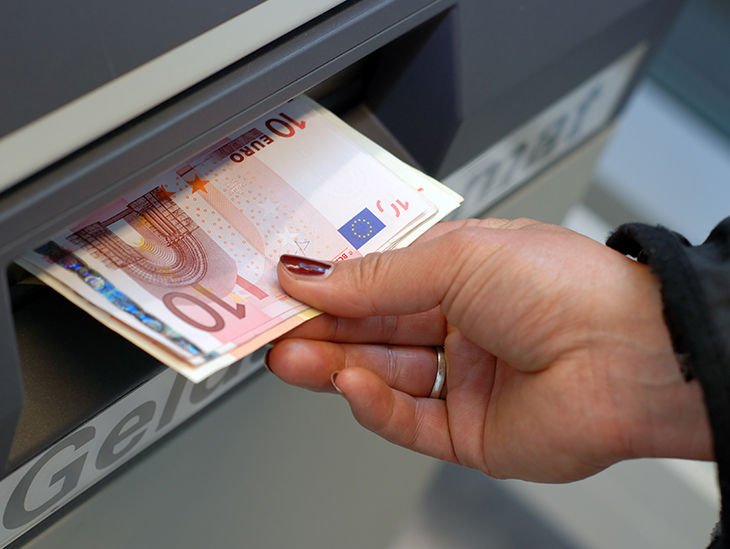 Eine Hand nimmt Bargeld aus einem Geldautomaten