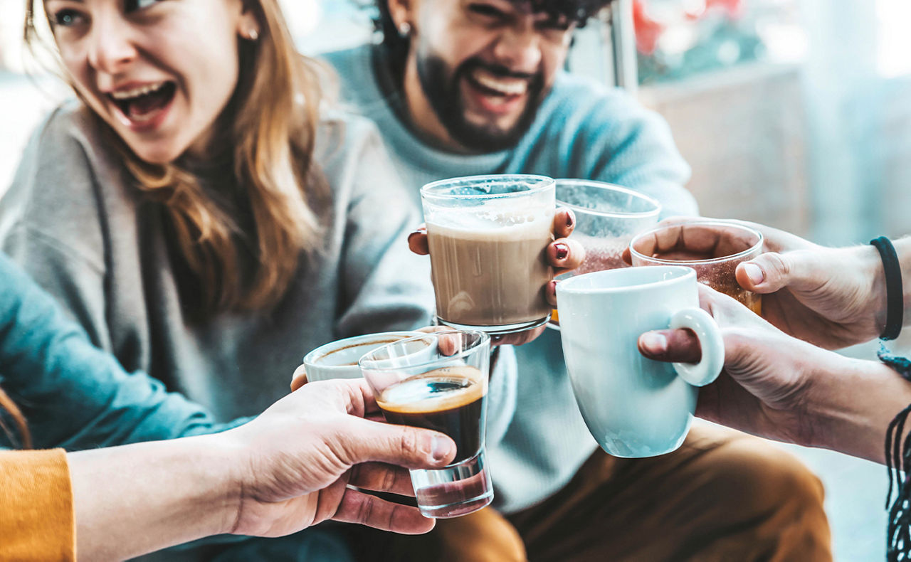 Mehrere Personen stoßen mit Kaffeetassen an