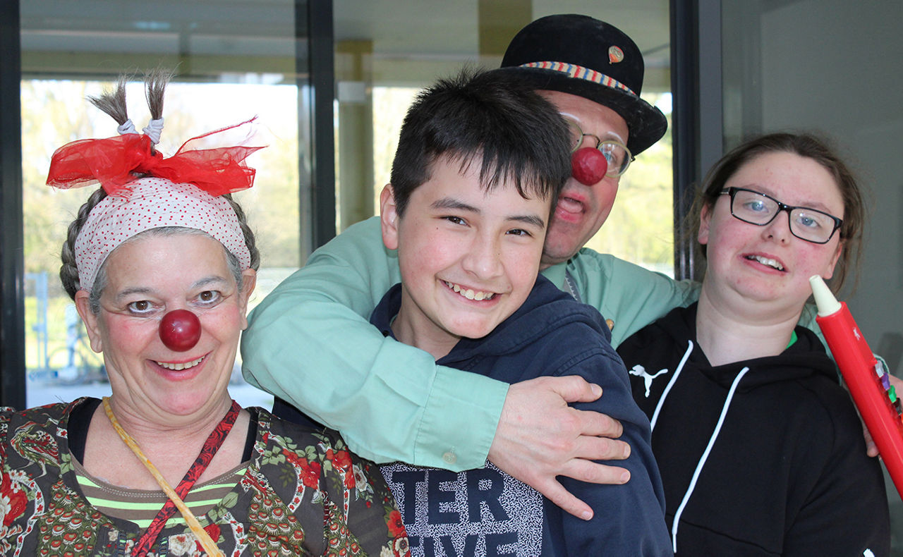 Zwei Kinder werden von verkleideten Clowns umarmt