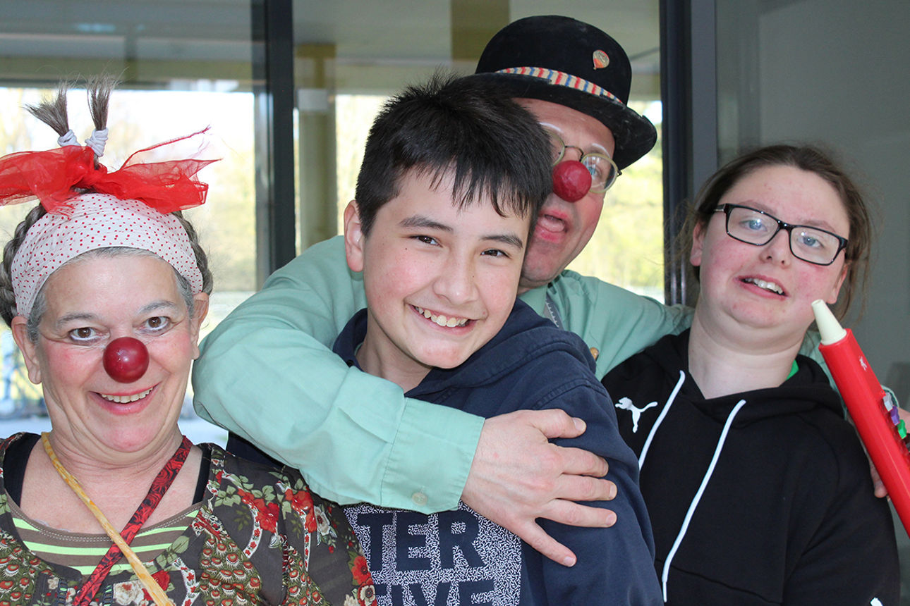 Zwei Kinder werden von verkleideten Clowns umarmt