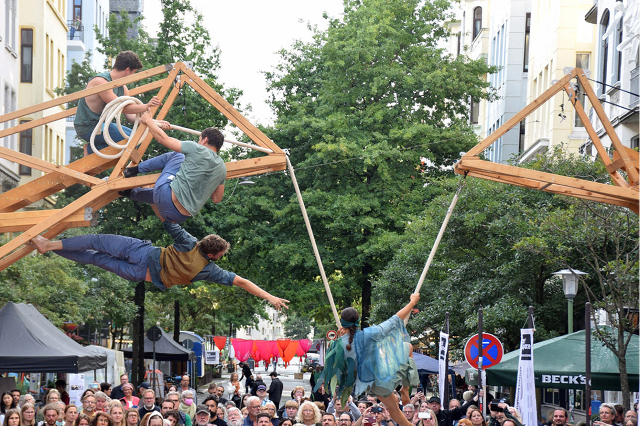 Mehrere Personen klettern akrobatisch vor einer größeren Menschenmenge auf einem Gerüst