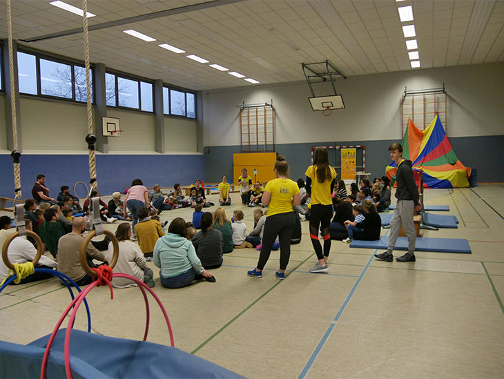 Kinder machen einen Sitzkreis in der Turnhalle