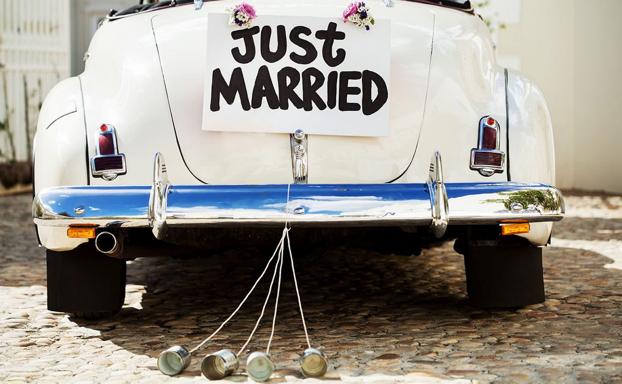 Ein altes Auto mit am Heck angehängten Dosen und einem Schild Just Married