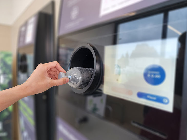 Pfandflasche wird in einen Pfandflaschenautomat geworfen