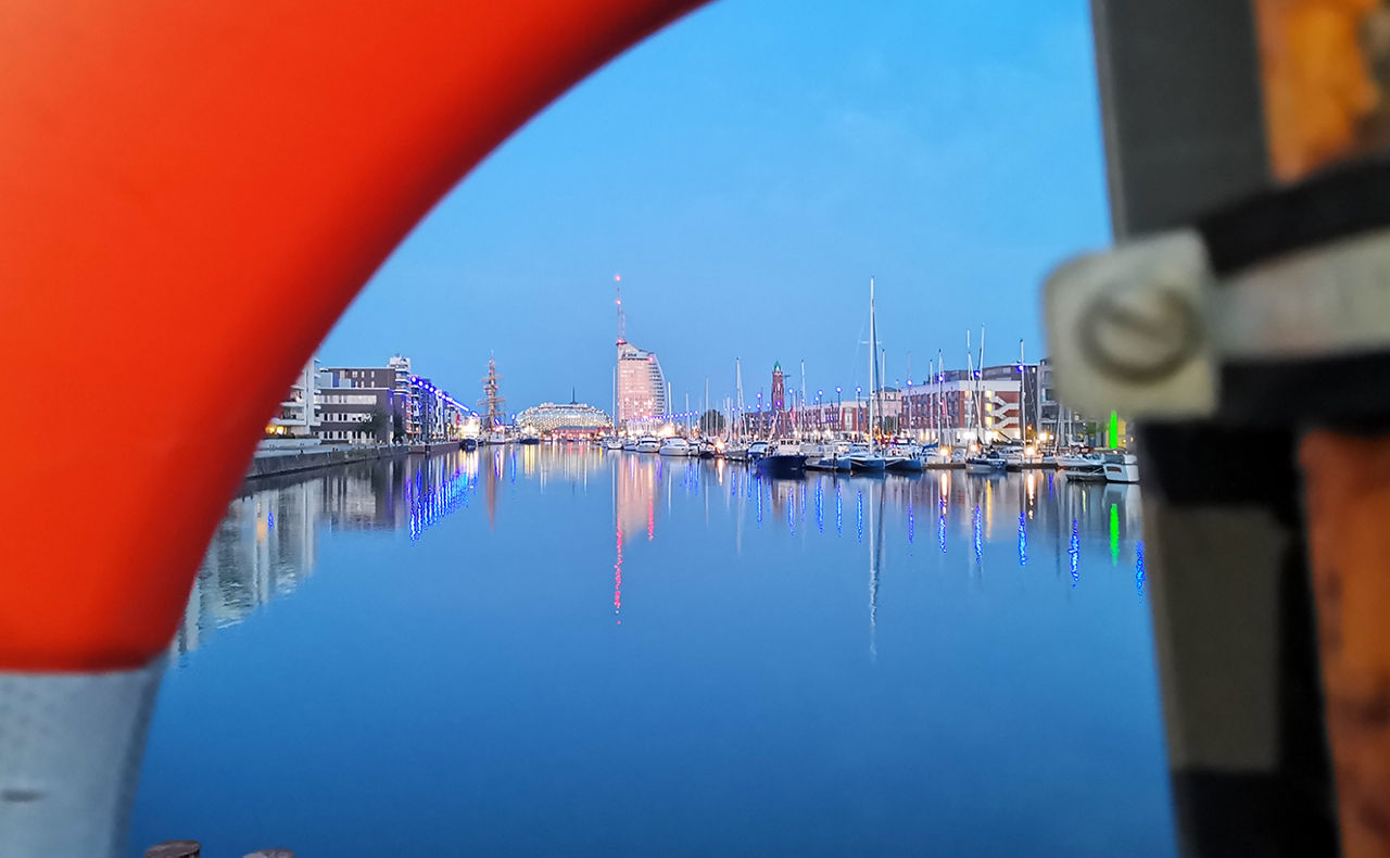 Hafen der Abends beleuchtet ist mit einer Stadt im Hintergrund
