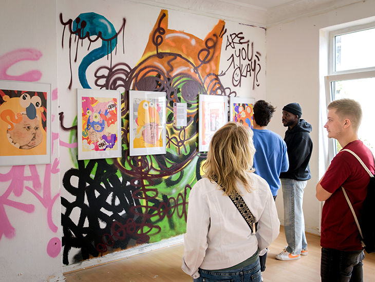 Personen schauen sich Kunst an einer Wand an