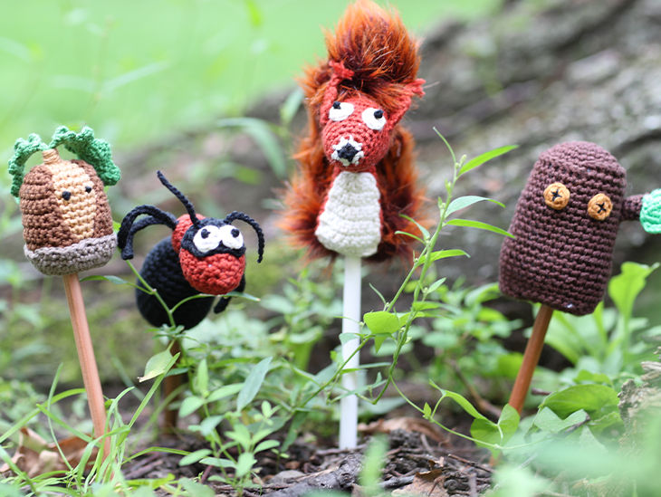 Kleine gehäkelte Tierfiguren stecken im Gras