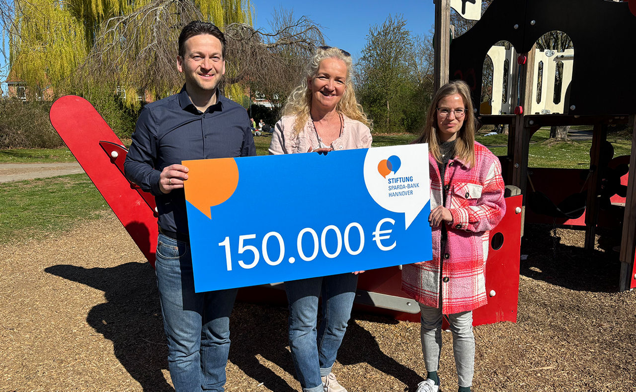 Drei Personen halten einen großen Scheck in der Hand mit der Aufschrift "15.000€"