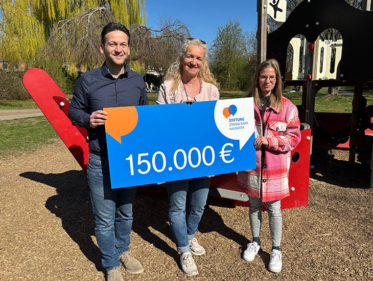 Drei Personen halten einen großen Scheck in der Hand mit der Aufschrift "15.000€"