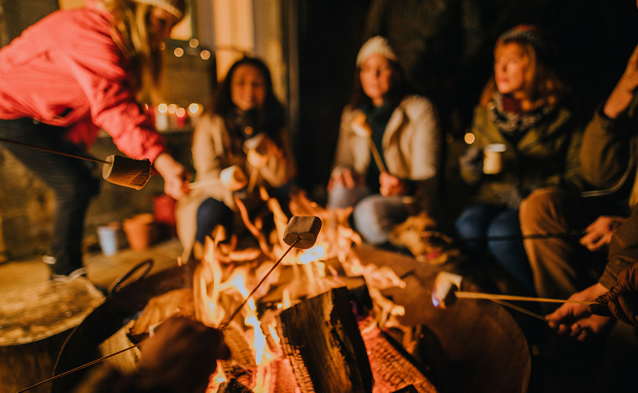 Personen sitzen zusammen am Feuer