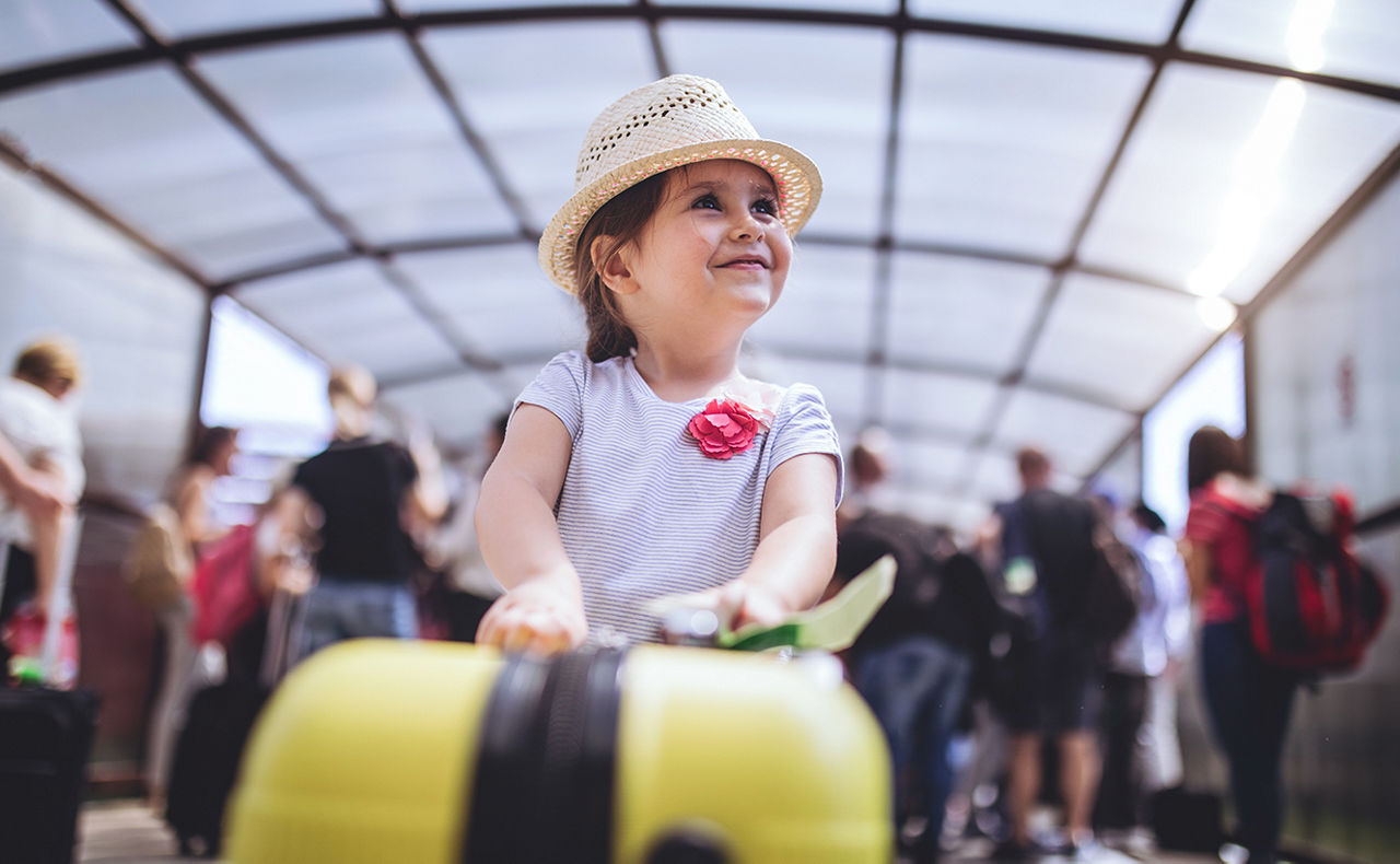 Kind mit Koffer in einer Flugschalterhalle