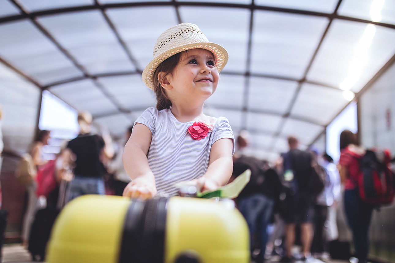 Kind mit Koffer in einer Flugschalterhalle