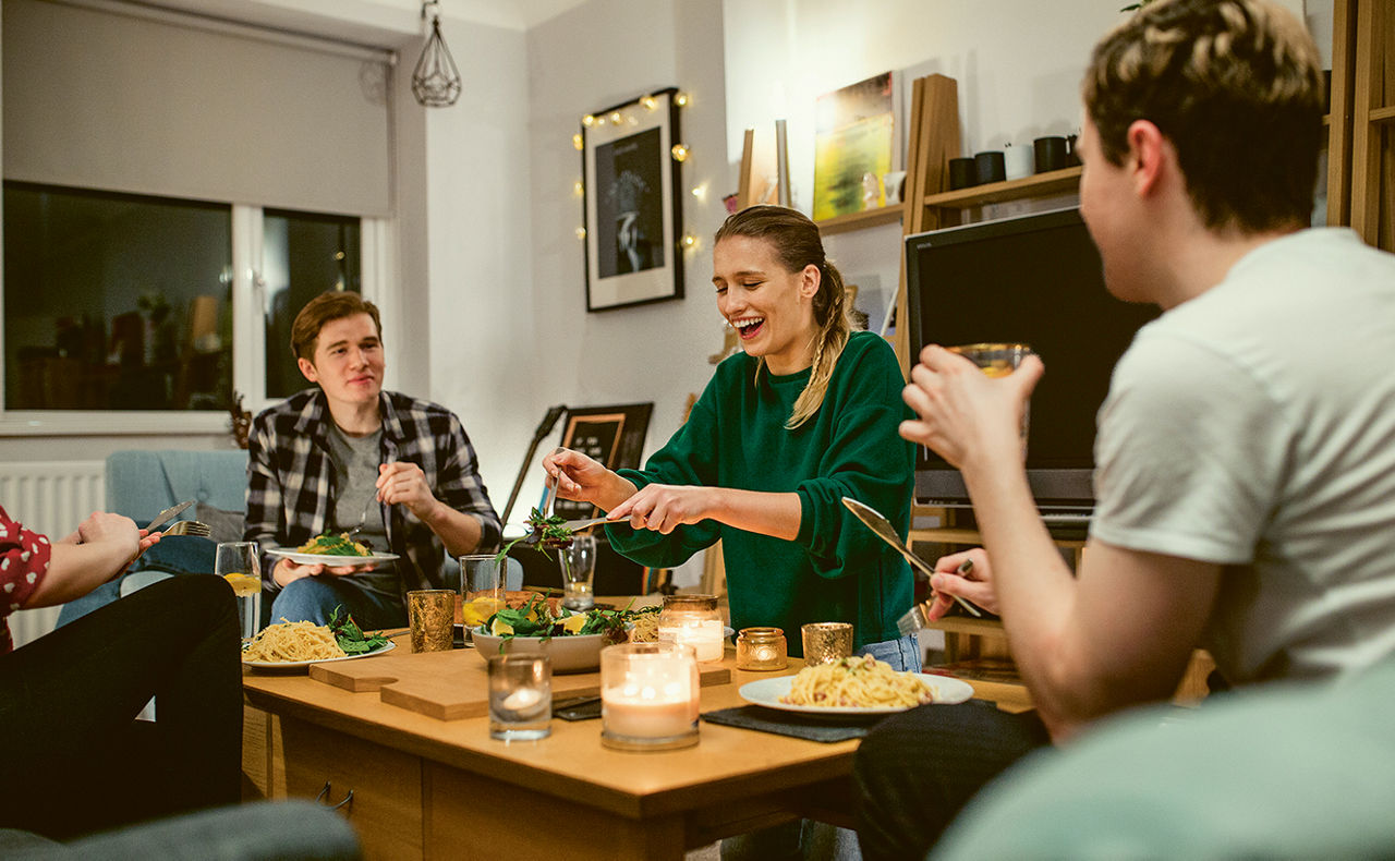 Personen sitzen an einem Tisch zusammen und essen und trinken