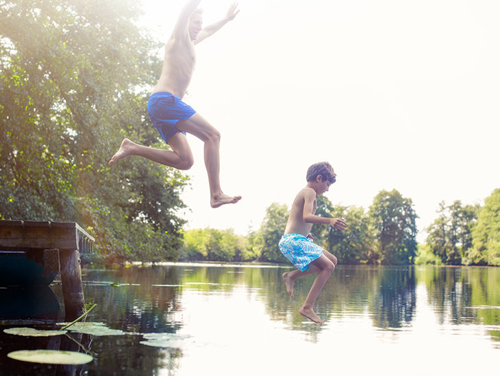 Zwei Kinder springen in einen Badesee