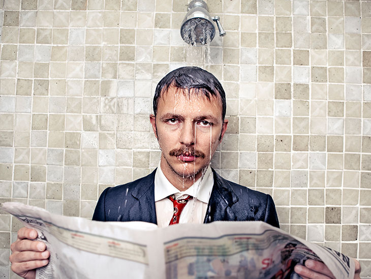 Mann steht im Anzug unter der Dusche