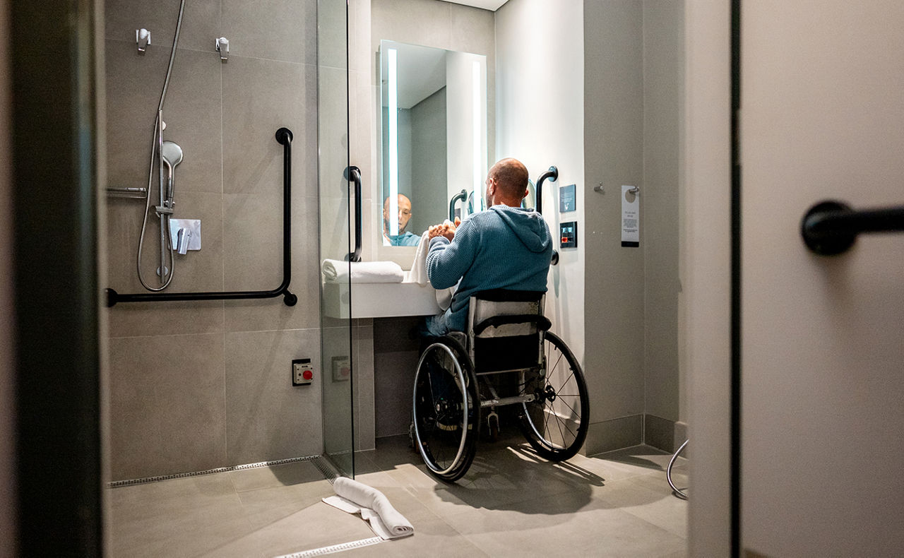 Mann im Rollstuhl im Badezimmer am Waschbecken