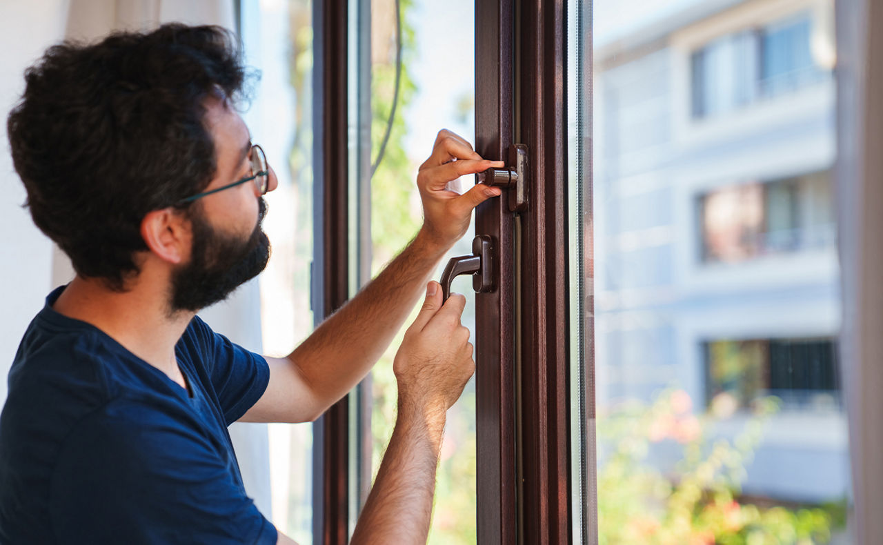 Mann macht Fenster einbruchssicher