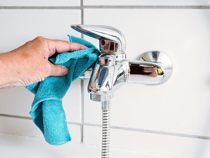 Jemand putzt einen Wasserhahn im Bad