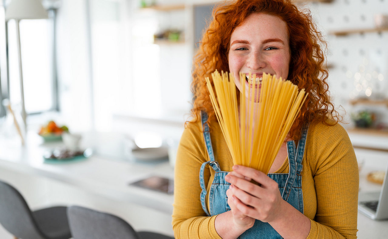 Frau hält Spaghetti wie einen Strauß vor ihr Gesicht