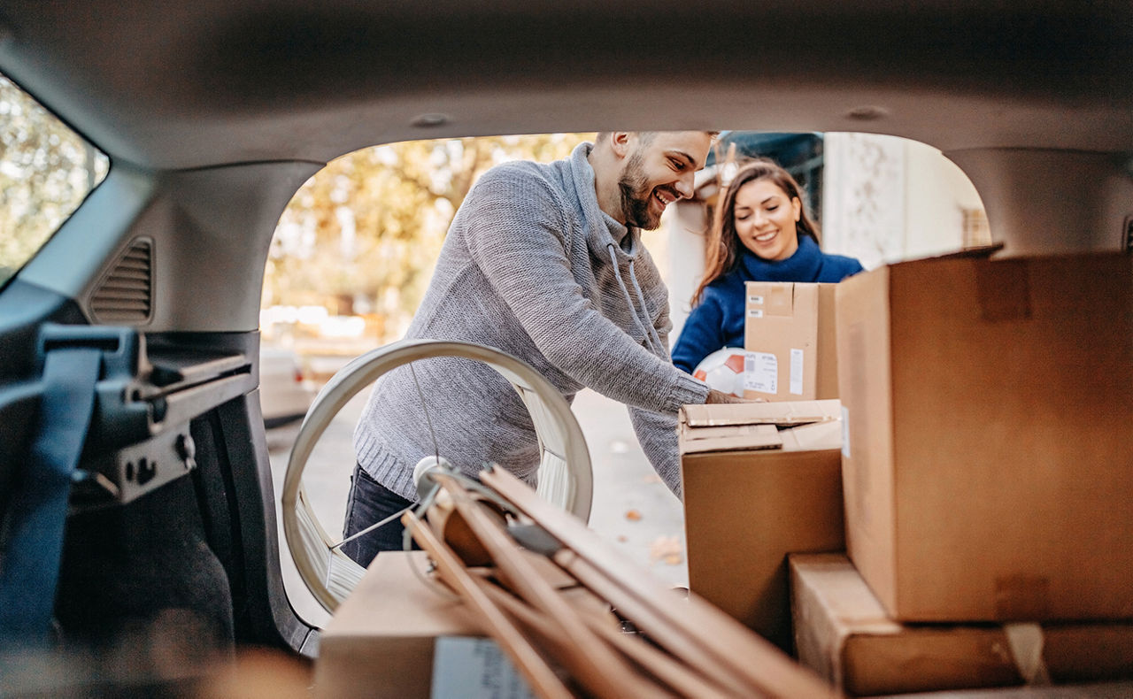 Paar packt gemeinsam ein Auto mit Umzugskartons ein