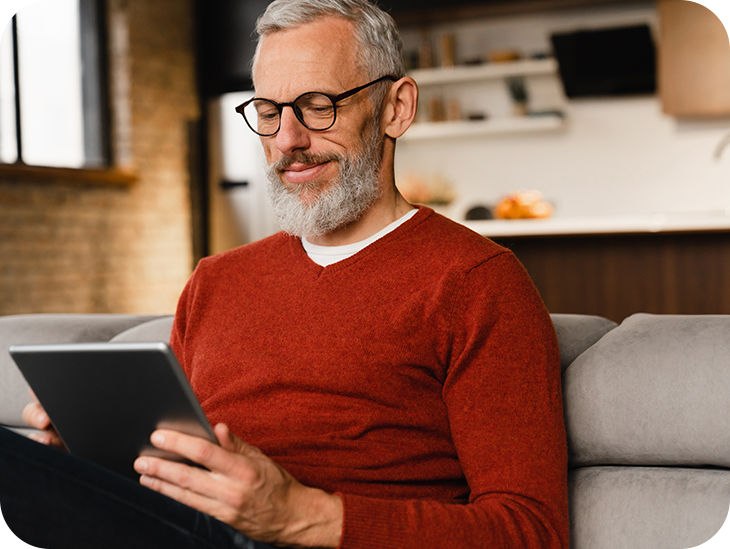 Mann sitzt auf dem Sofa vor einem Tablet