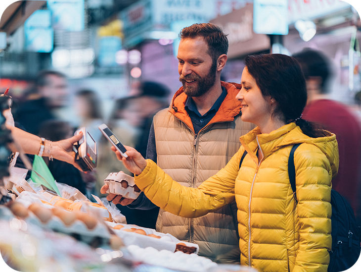Paar bezahlt an einem Marktstand mit einem Handy