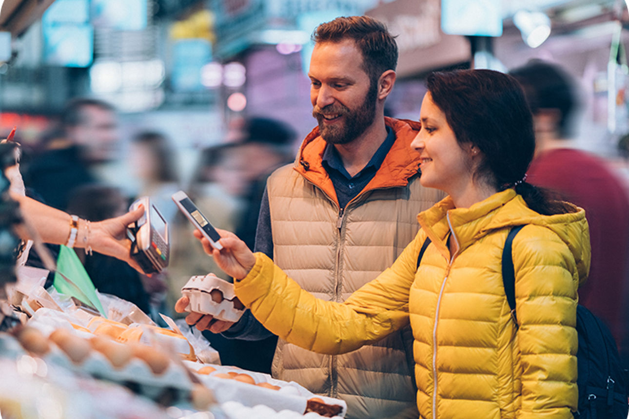 Paar bezahlt an einem Marktstand mit einem Handy