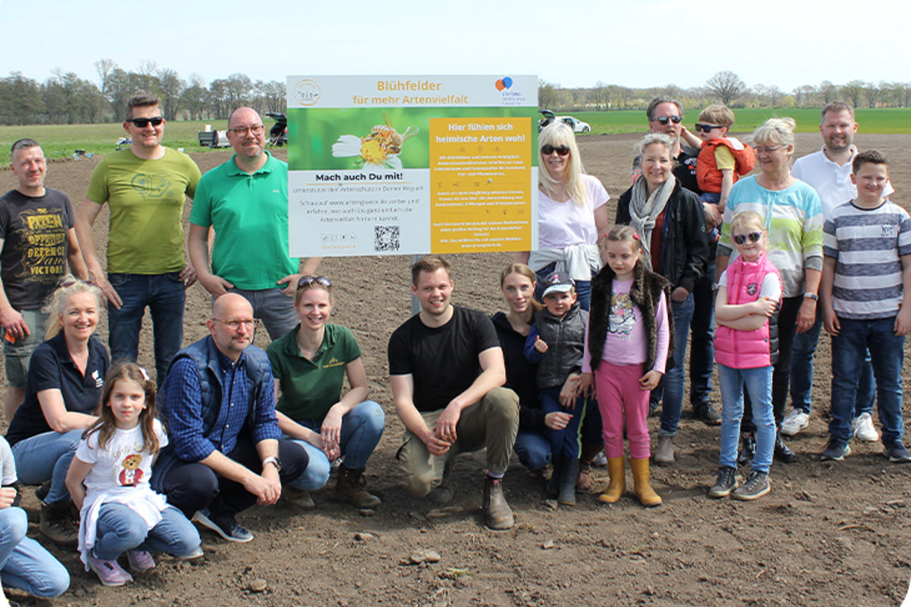 Gruppe von mehreren Personen steht auf einem Feld 