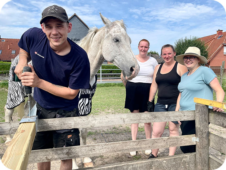 Vier Personen und ein Pferd auf einem Reiterhof