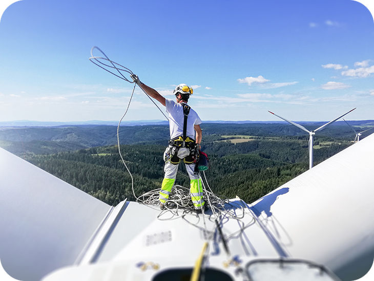 Mann steht befestigt auf einer Windkraftanlage