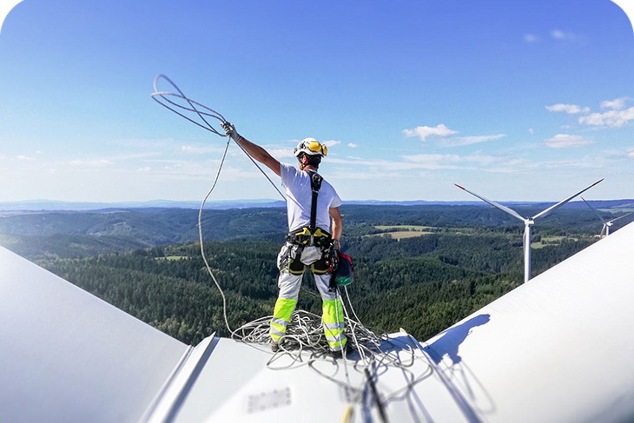 Mann steht befestigt auf einer Windkraftanlage